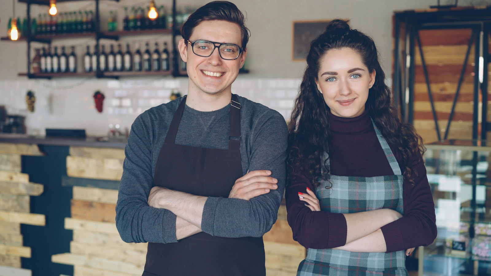 Two smiling cafe owners standing in their coffee shop