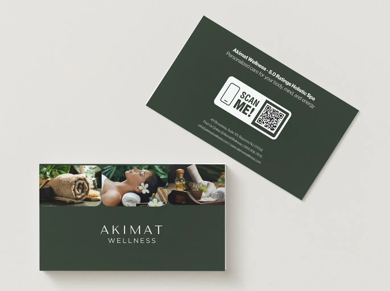 Two dark green Akimat Wellness business cards, one showing spa imagery and the logo and the other a Scan Me QR code panel.