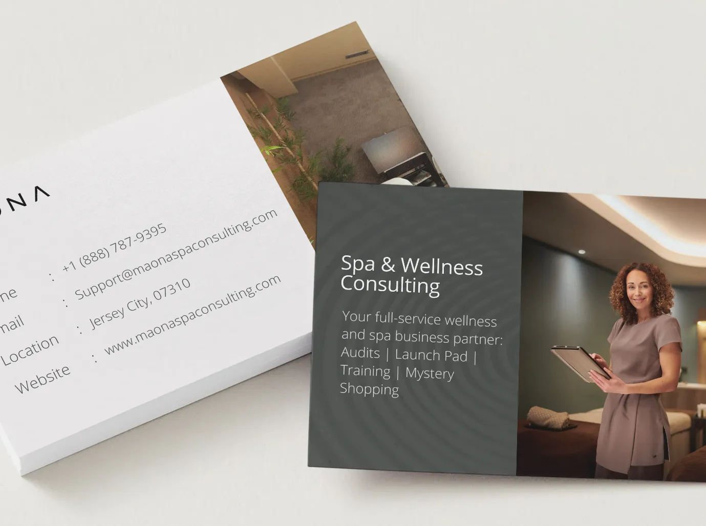 Two business cards for a spa and wellness consulting firm, one with contact details and one in charcoal with a consultant holding a clipboard in a treatment room.