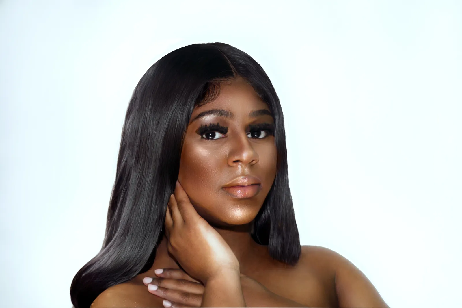 A woman with long straight black hair rests a hand on her neck against a bright white studio backdrop.