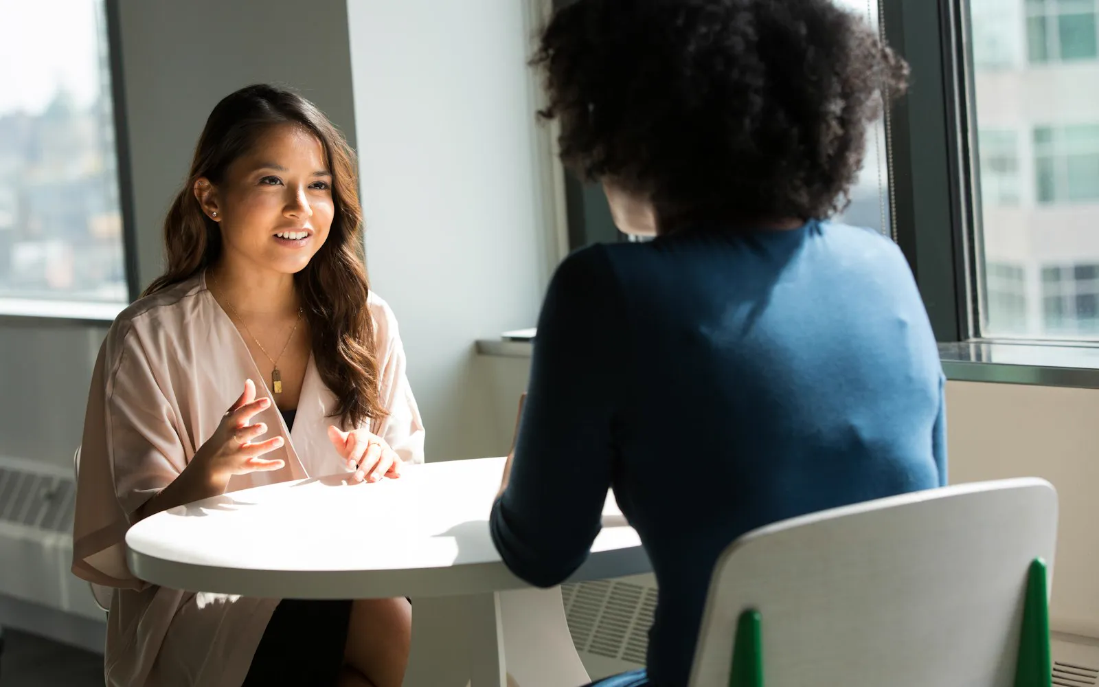 Two women talking through a plan at a table in a bright office